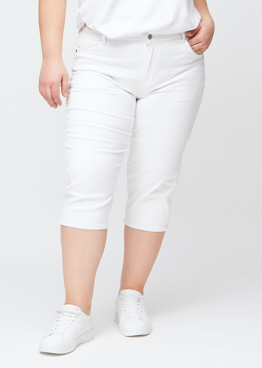 White slim capris, colour Marguerites, with a tight fit and length just below the knee, seen from the front on a plus-size model.