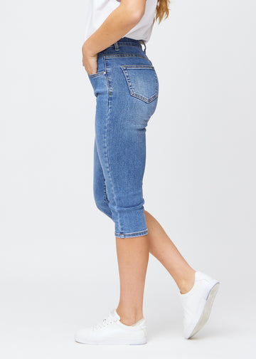 Slim capris for women in blue denim, color Rivers. Side view on a model, showing the tailored fit and mid-rise waist.