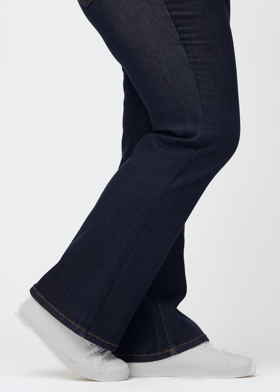 Deep dark blue denim jeans for women in the color Midnights with a bootcut fit seen in close-up at the ankles on a plus-size model to show the slight flare.