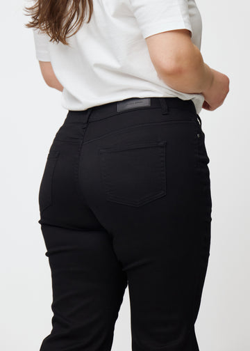 Black mid-rise bootcut jeans in Ravens. Close-up back view on a plus-size model, showing the details.