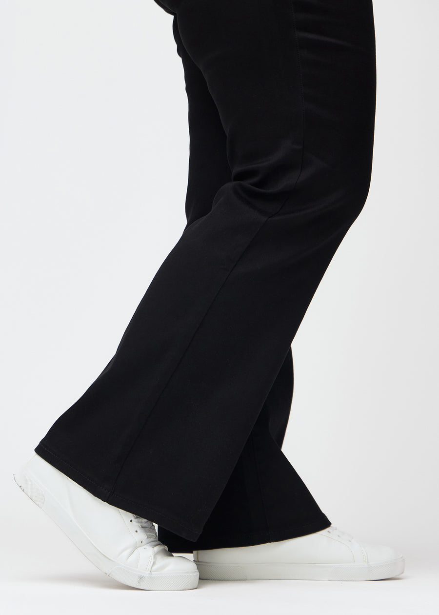 The ankles of a plus-size model, so the slight flare in the pant leg can be seen, in a Bootcut fit.
