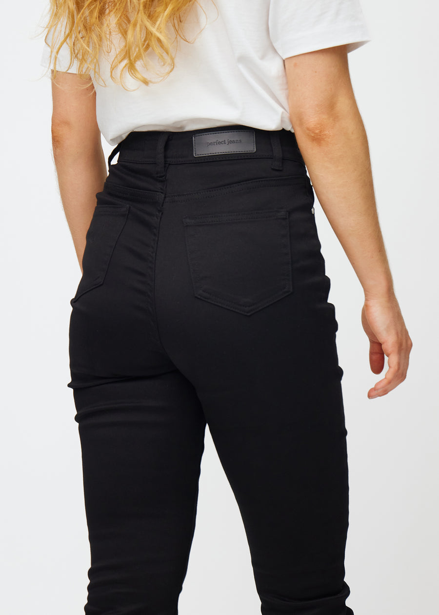 Black high-waisted slim jeans seen from the back close up to show details.