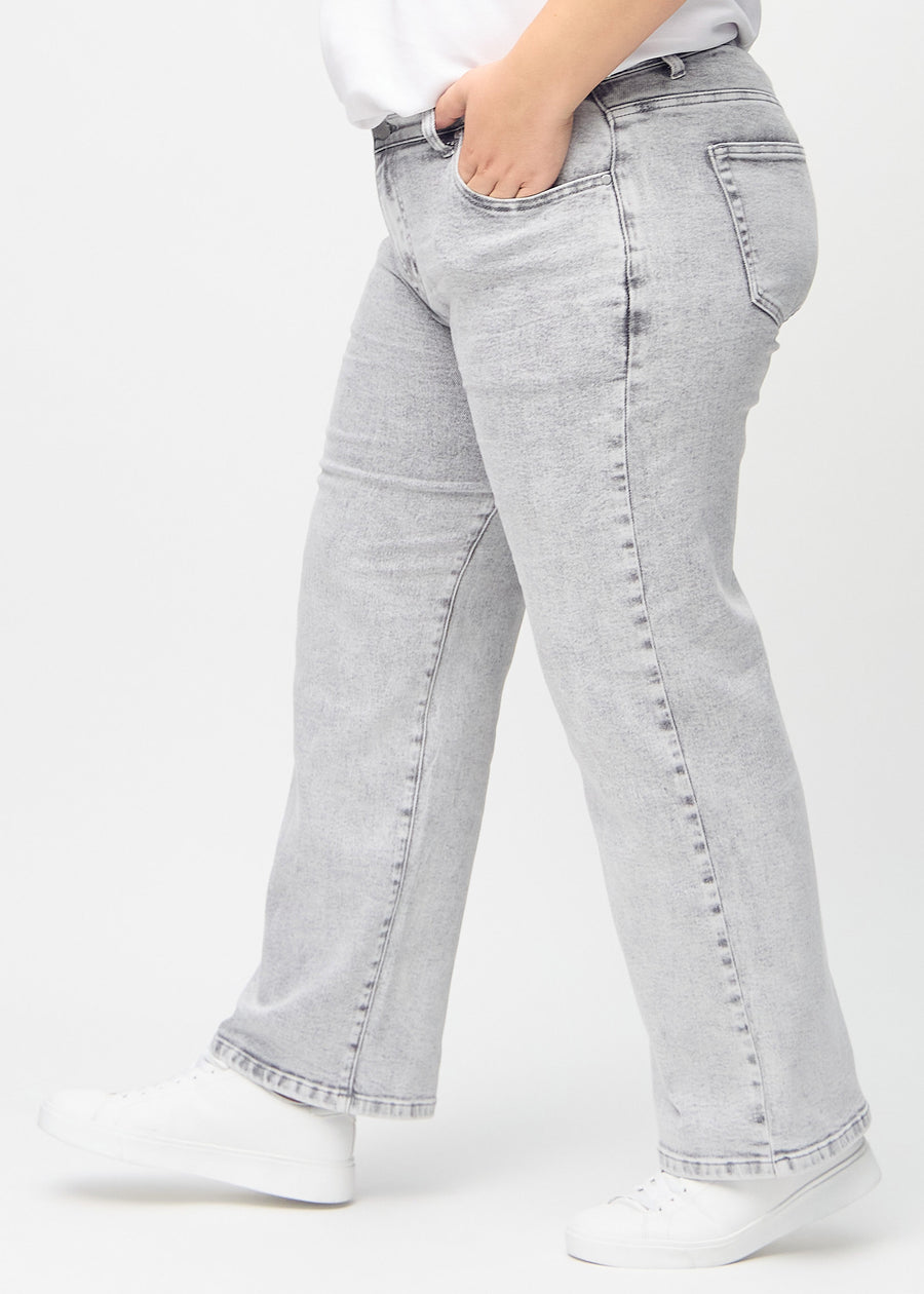 Light grey denim loose jeans seen from the side on a plus-size model.