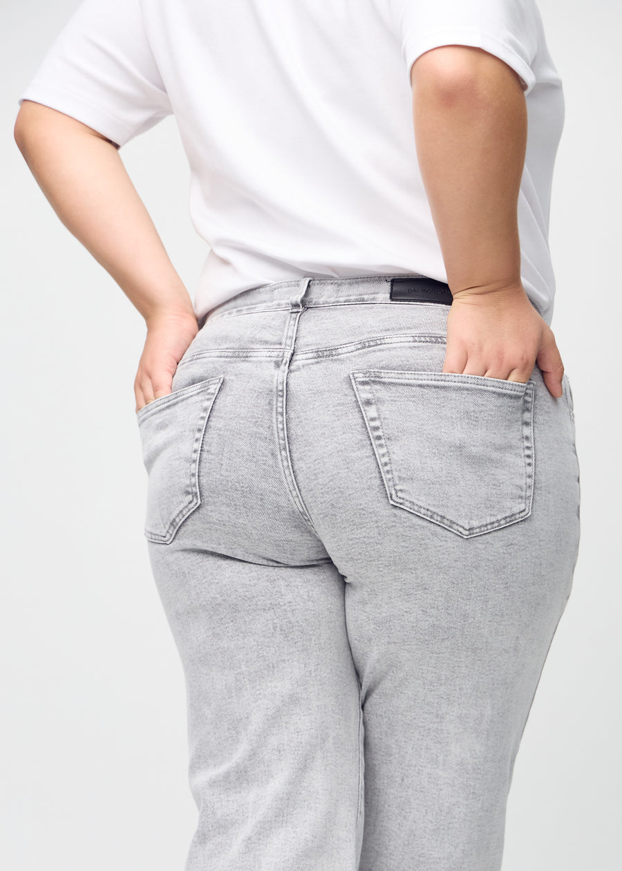 Light grey denim loose jeans seen from the back close up on a plus-size model to show details.