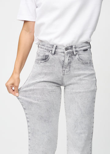 The model stretches the jeans at the thigh to show the stretch.