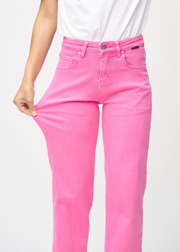 Loose jeans for women in light pink, color Flamingos. A model stretches the denim at the thigh to show the fabric&
