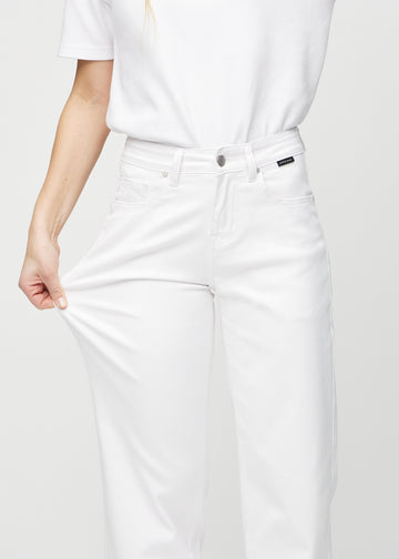 The model stretches the jeans at the thigh to show the stretch.