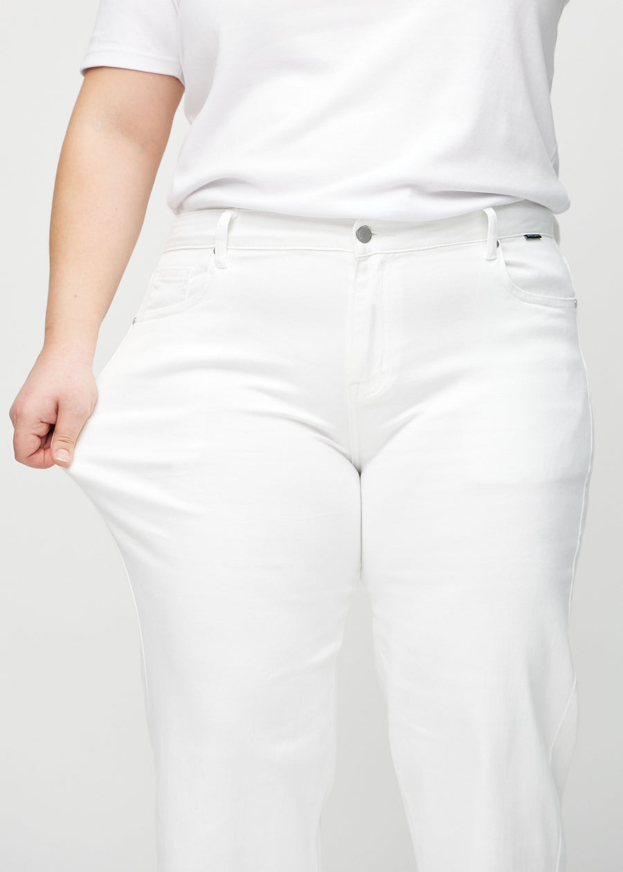 The plus-size model stretches the jeans at the thigh to show the stretch.