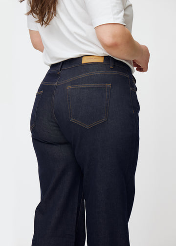 Deep dark blue denim jeans for women in the color Midnights shown from the back in a close-up on a plus-size model.