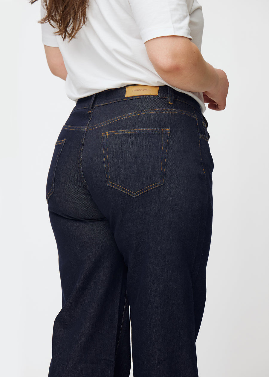 Deep dark blue denim jeans for women in the color Midnights shown from the back in a close-up on a plus-size model.