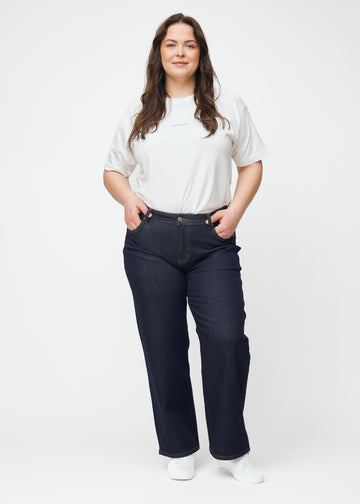 Full image of a plus-size model in deep dark blue denim jeans for women in the color Midnights with a loose fit.