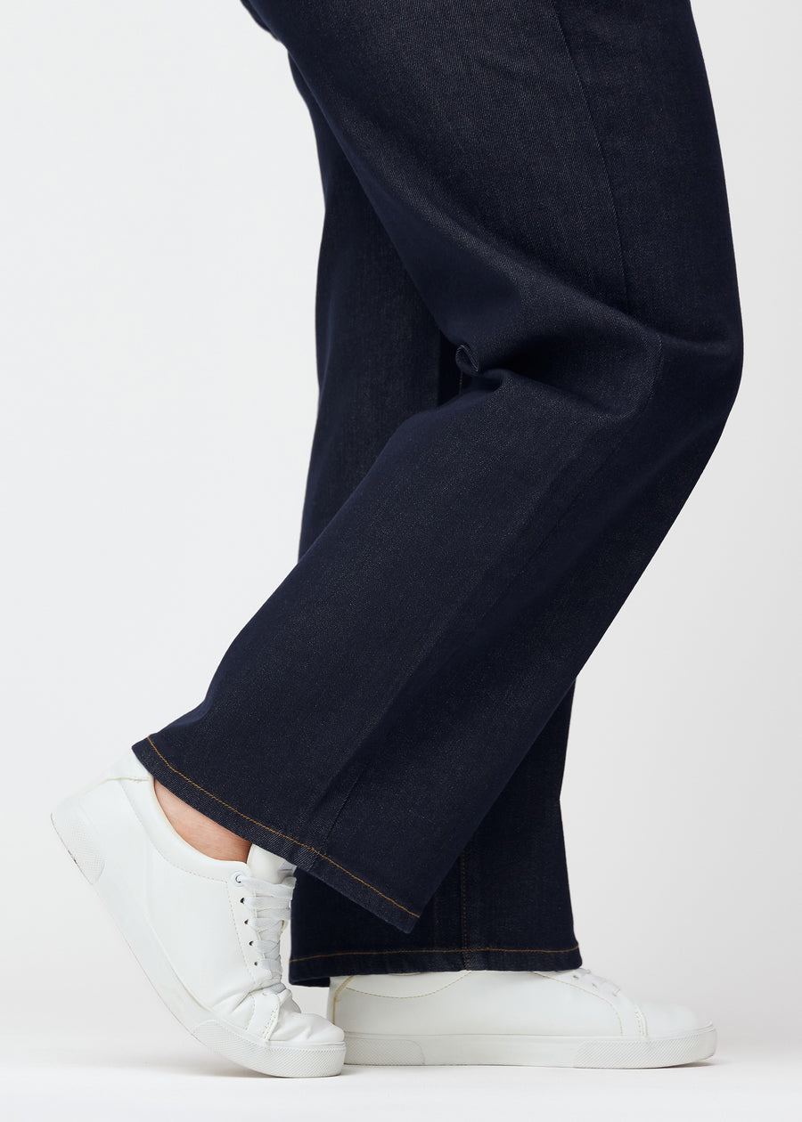 Deep dark blue denim jeans for women in the color Midnights with a loose fit, shown close up at the ankles on a plus-size model to show the wide hem.