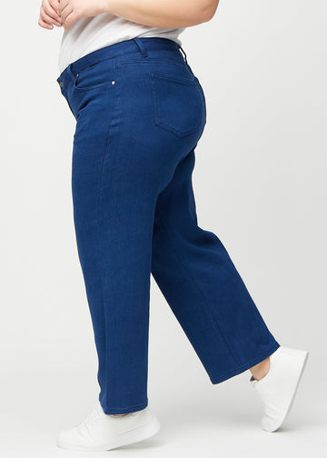 Dark blue loose jeans seen from the side on a plus-size model.