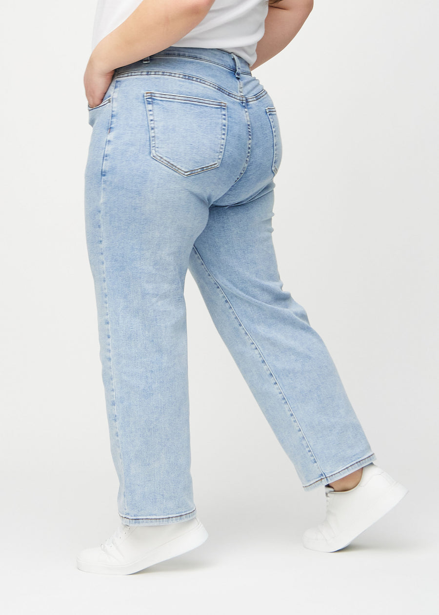 Light denim loose jeans seen from the side on a plus-size model.