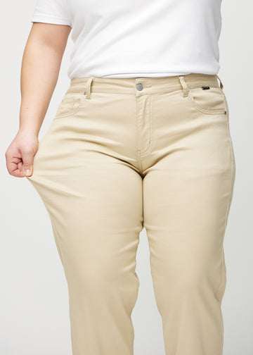 Regular jeans for women in beige, color Gazelles. A plus-size model stretches the fabric at the thigh to show its stretch.