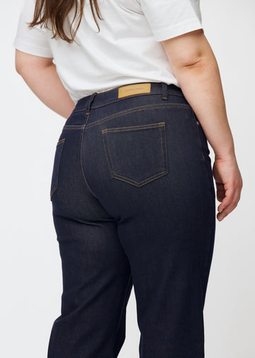 Deep dark blue denim jeans for women in the color Midnights, seen from the back close up on a plus-size model.
