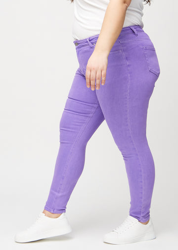 Skinny jeans for women in purple, color Lavenders. Side view on a plus-size model.
