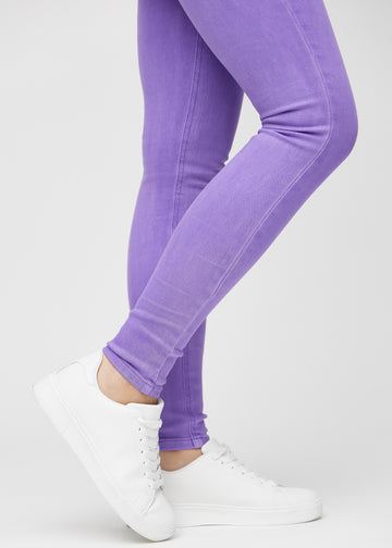 Skinny jeans for women in purple, color Lavenders. Close-up of the snug-fitting leg openings at the ankles on a model.