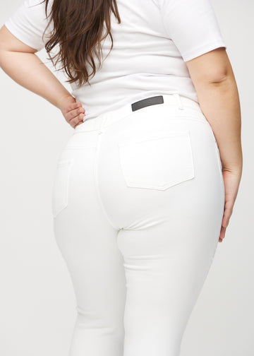 White skinny jeans seen from the back in a close-up on a plus-size model to show details.