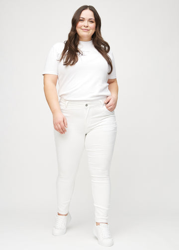Full image of a plus-size model in white skinny jeans.