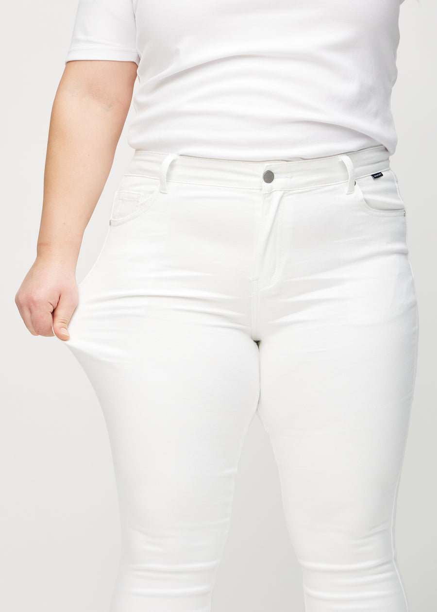 The plus-size model stretches the jeans at the thigh to show the stretch.