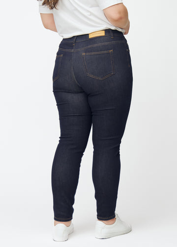 Deep dark blue denim jeans for women in the color Midnights viewed from the back on a plus-size model.