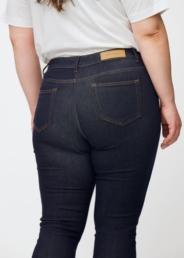 Deep dark blue denim jeans for women in the color Midnights viewed from the back in close-up on a plus-size model.