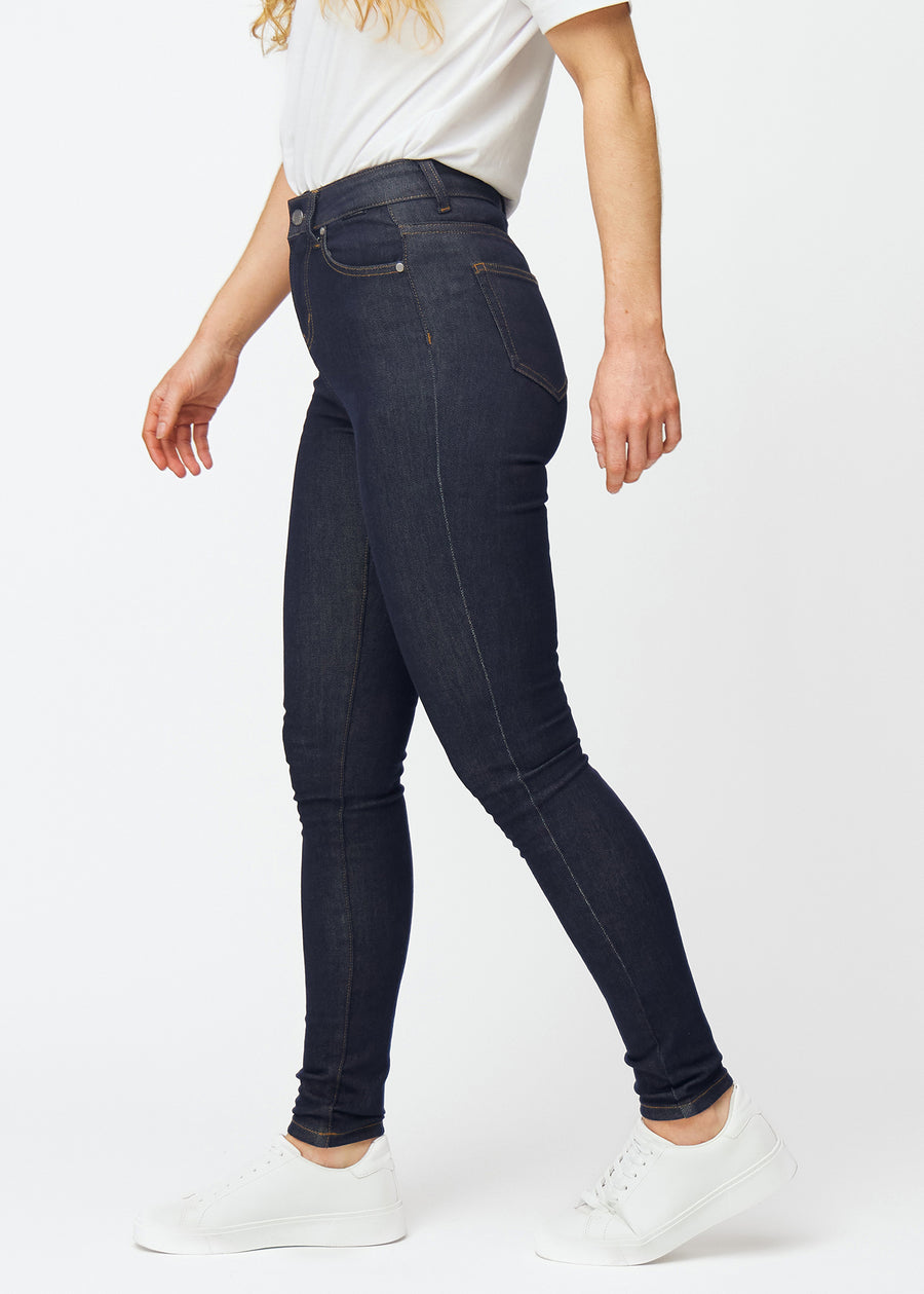 Deep dark blue denim jeans for women in the color Midnights with a skinny fit, viewed from the side on a model.