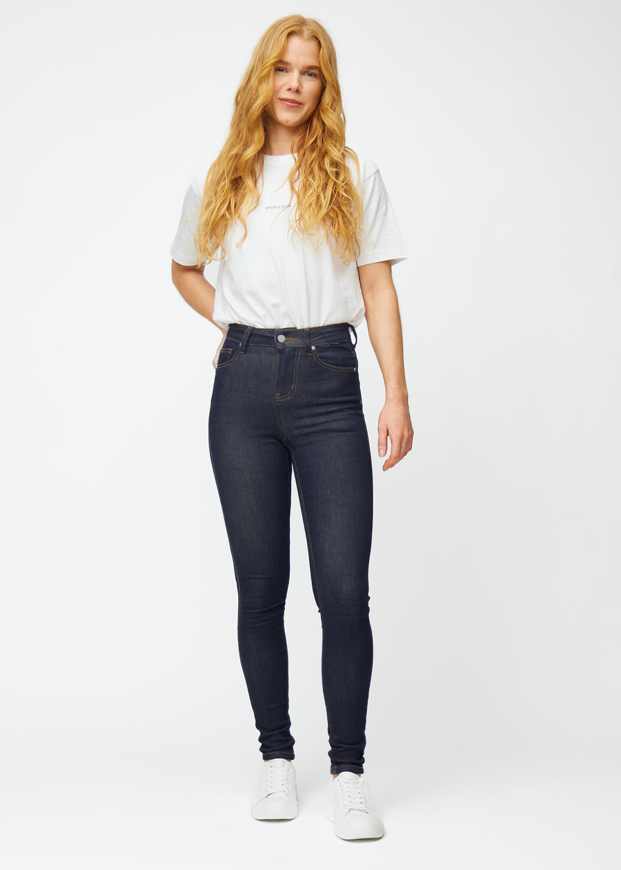 Full image of a model in deep dark blue denim jeans for women in the color Midnights with a skinny fit.