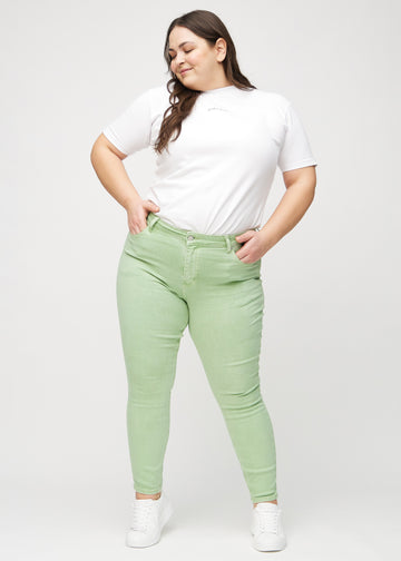 Skinny jeans for women in light green, color Mints. Full-length view of a plus-size model in the jeans.