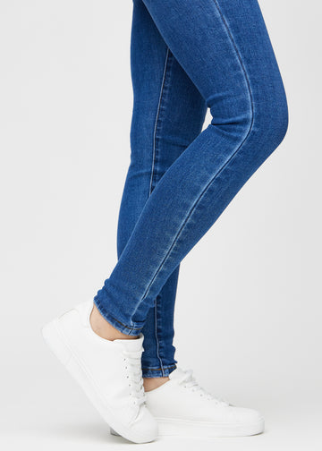 Skinny jeans for women in dark blue, color Oceans. Close-up of the snug-fitting leg openings at the ankles on a model.