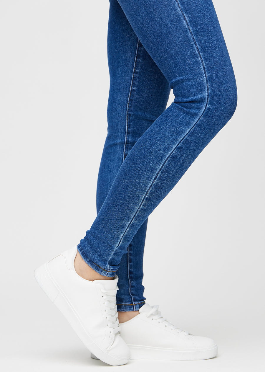Skinny jeans for women in dark blue, color Oceans. Close-up of the snug-fitting leg openings at the ankles on a model.