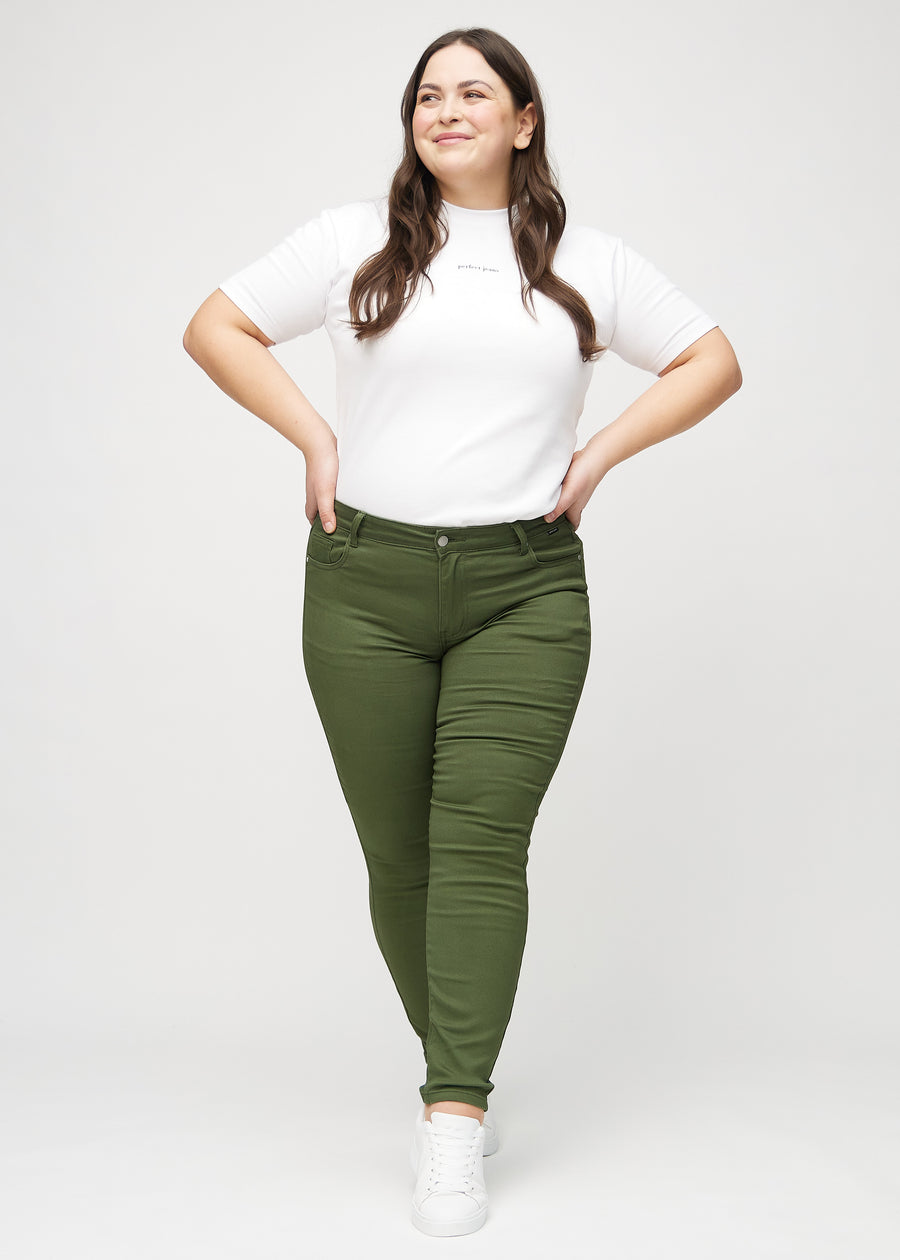 Skinny jeans for women in dark green, color Renewals. Full-length view of a plus-size model in the jeans.