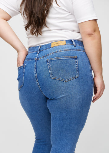 Skinny jeans for women in blue, color Rivers. Close-up back view on a plus-size model, showing details.