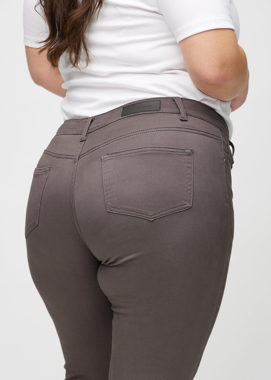Grey-brown skinny jeans seen from the back close up on a plus-size model to show details.