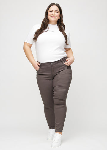 Full image of a plus-size model in grey-brown skinny jeans.