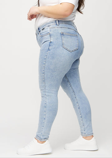 Skinny jeans for women in light blue, color Waves. Side view on a plus-size model.