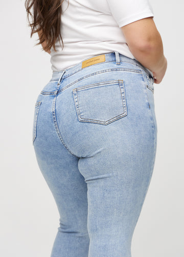 Skinny jeans for women in light blue, color Waves. Close-up back view on a plus-size model, showing details.