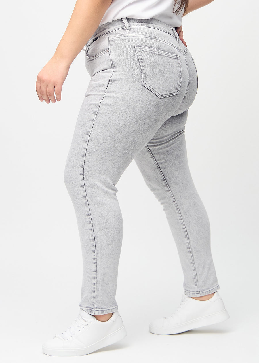 Light grey denim slim jeans seen from the side on a plus-size model.