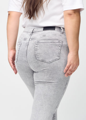 Light grey denim slim jeans seen from the back close up on a plus-size model to show details.