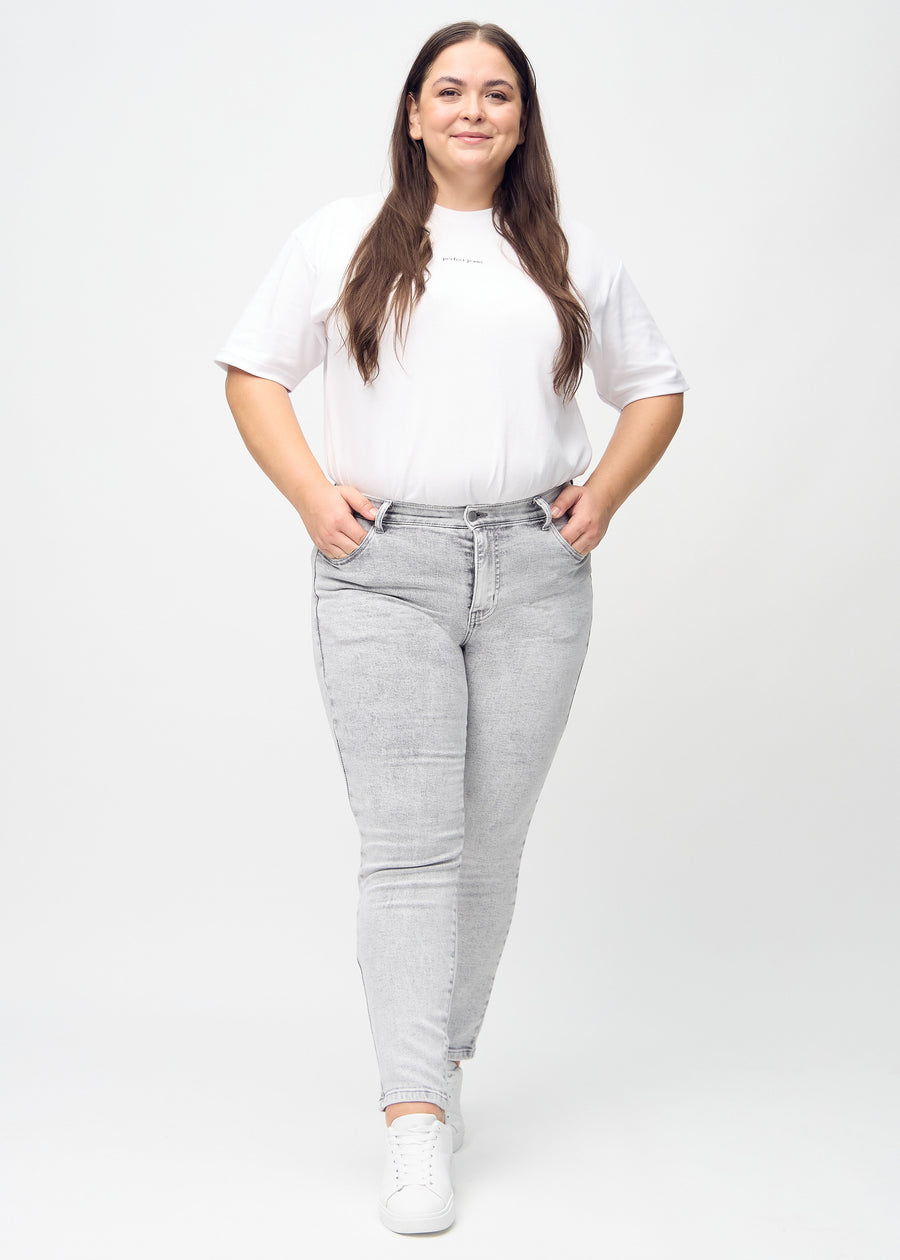 Full image of a plus-size model in light grey denim slim jeans.