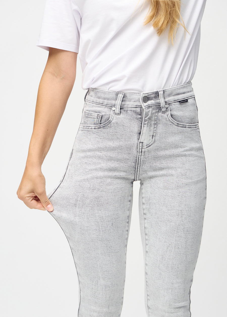 The model stretches the jeans at the thigh to show the stretch.