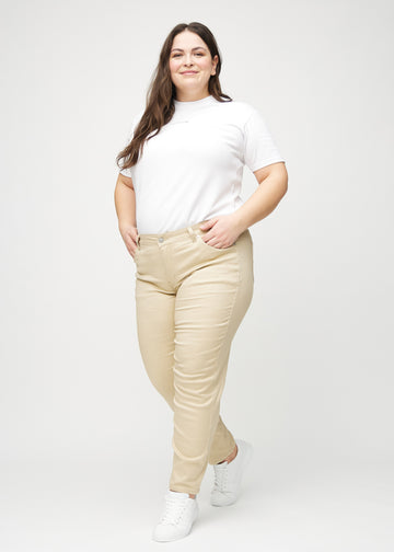Full image of a plus-size model in beige slim jeans.