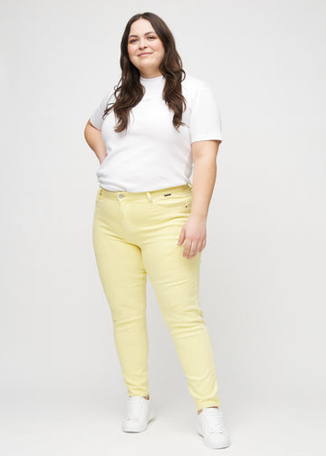 Slim jeans for women in light yellow, color Lemonades. Full-length view of a plus-size model wearing the jeans.