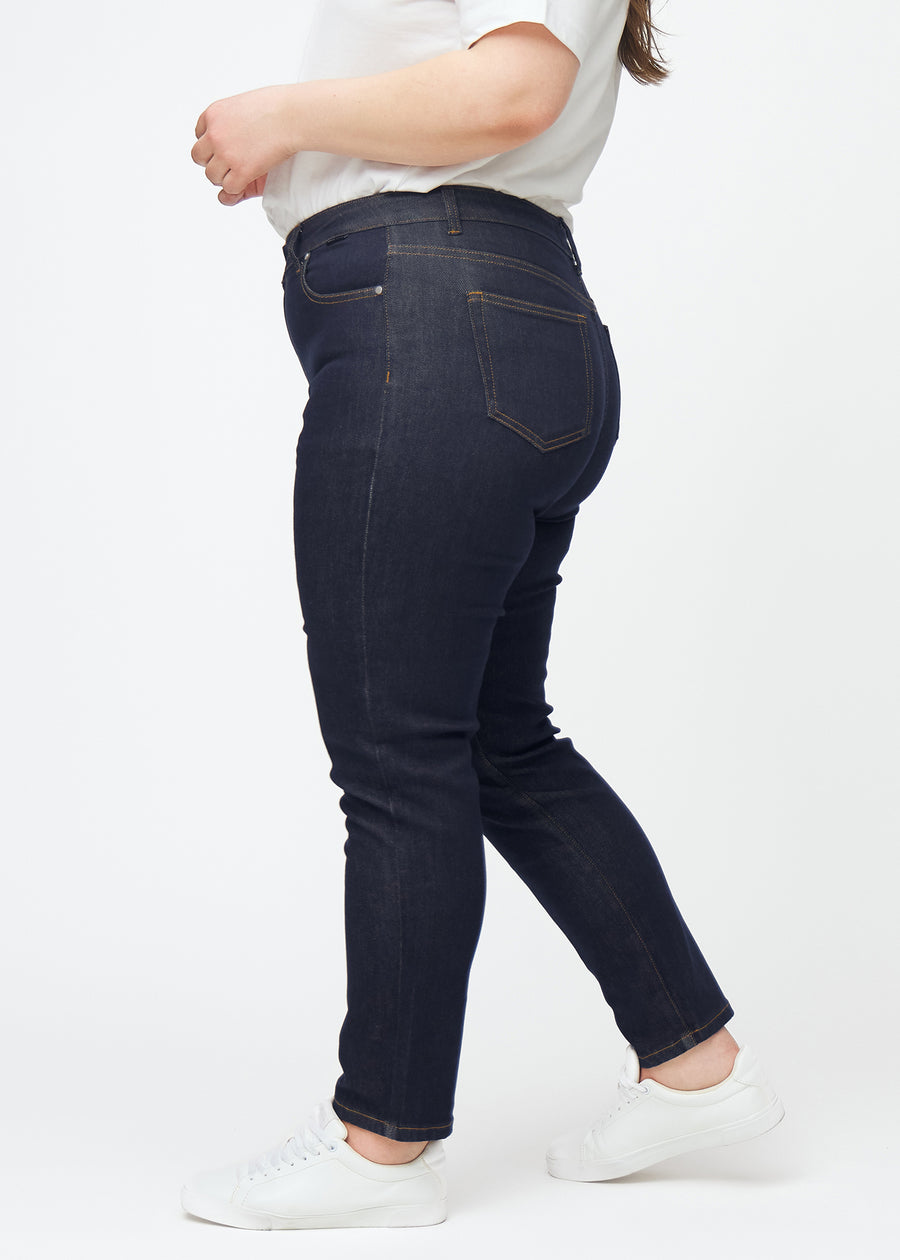 Deep dark blue denim jeans for women in the color Midnights with a slim fit seen from the side on a plus-size model.