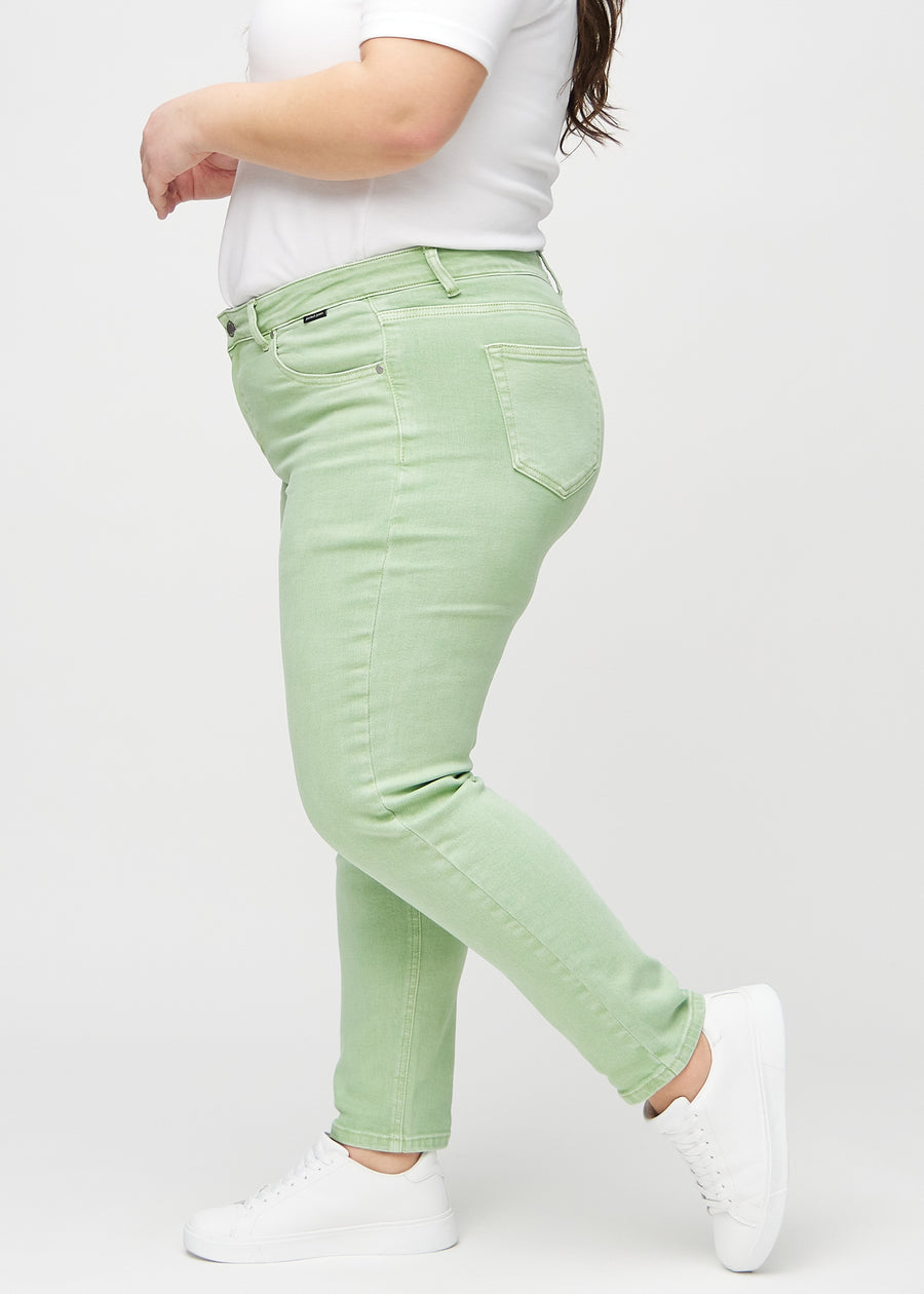 Light green slim jeans seen from the side on a plus-size model.
