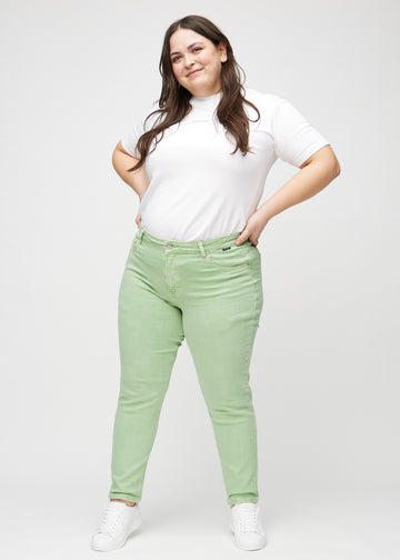 Full image of a plus-size model in light green slim jeans.