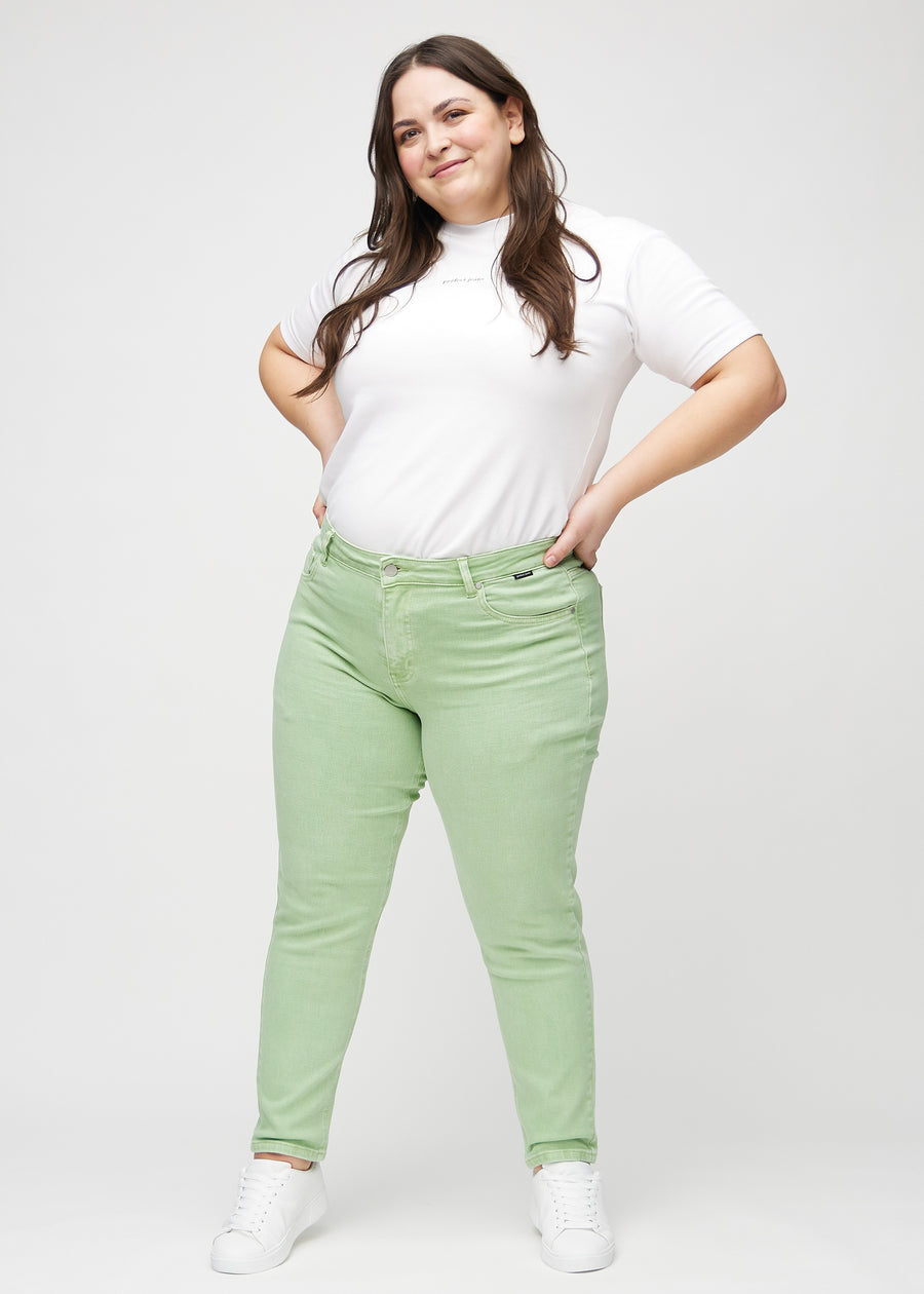 Full image of a plus-size model in light green slim jeans.