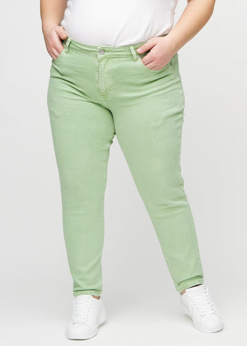 Light green slim jeans, model name Mints, which fit closely to the leg, though slightly looser at the ankle, on a plus-size model, seen from the front.