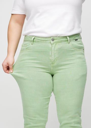 The plus-size model stretches the jeans at the thigh to show the stretch.